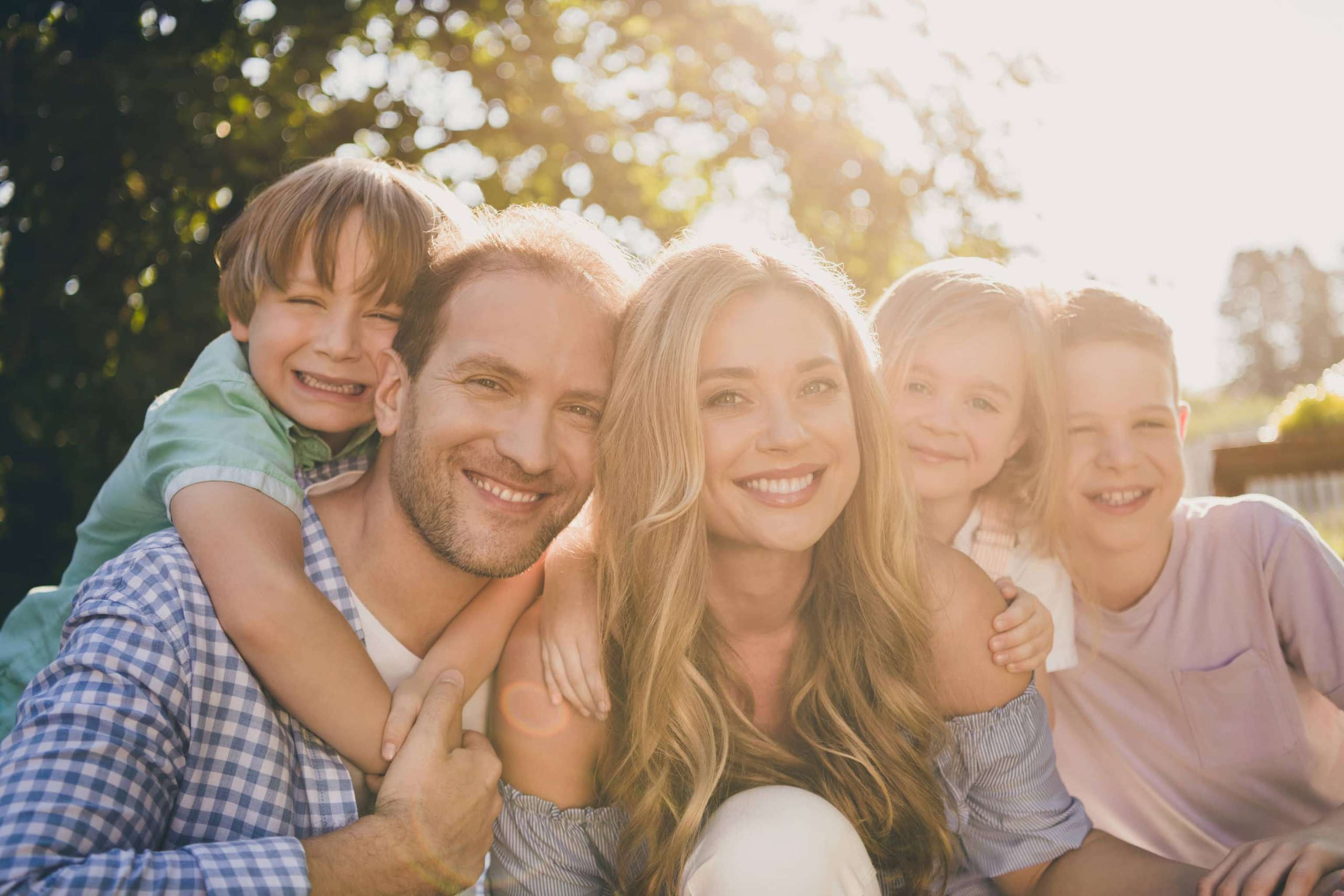 Dream Summer Weekend Countryside Backyard Relax Concept. Mom Dad And Their Little Kids Girls Boys Hug Embrace Enjoy Sunset Evening Park Garden Day Outdoors