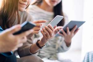 Group Of People Using And Looking At Mobile Phone And Tablet Pc While Sitting Together
