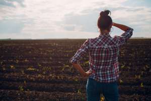Woman Farmer Standing And Looking Agricultural Field Soil