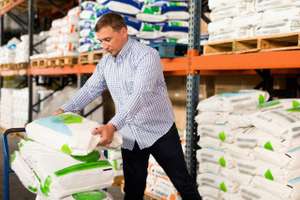 Man Choosing Compost Soil In Plastic Bags In Hypermarket