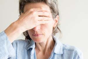 Close Up Of Middle Aged Woman With Hand Covering Eyes
