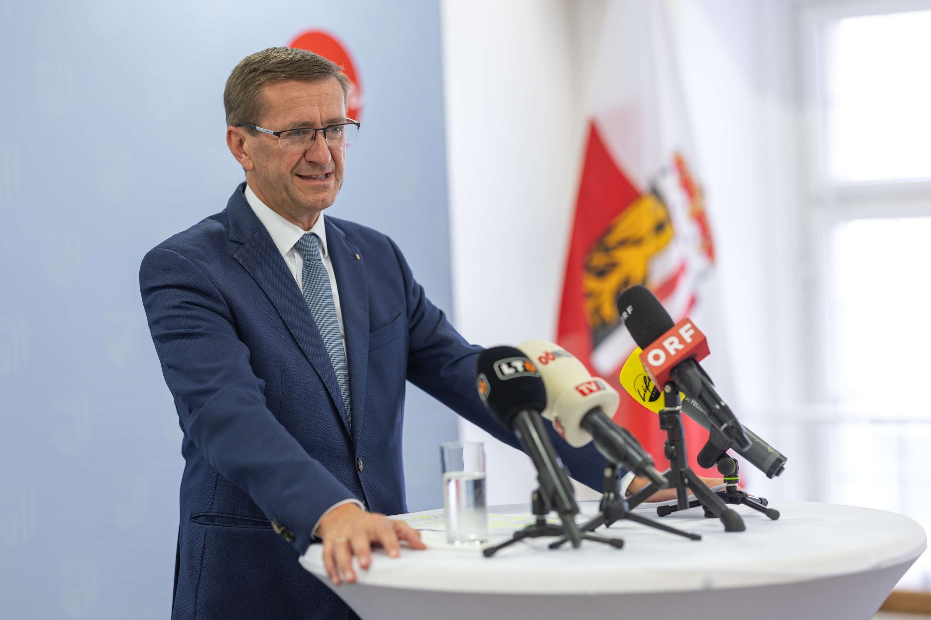 Oberösterreichs Wirtschaftslandesrat Markus Achleitner vor Mikrofonen am Rednerpult.