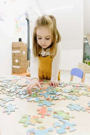 Ein kind setzt auf einem Tisch ein Puzzle zusammen