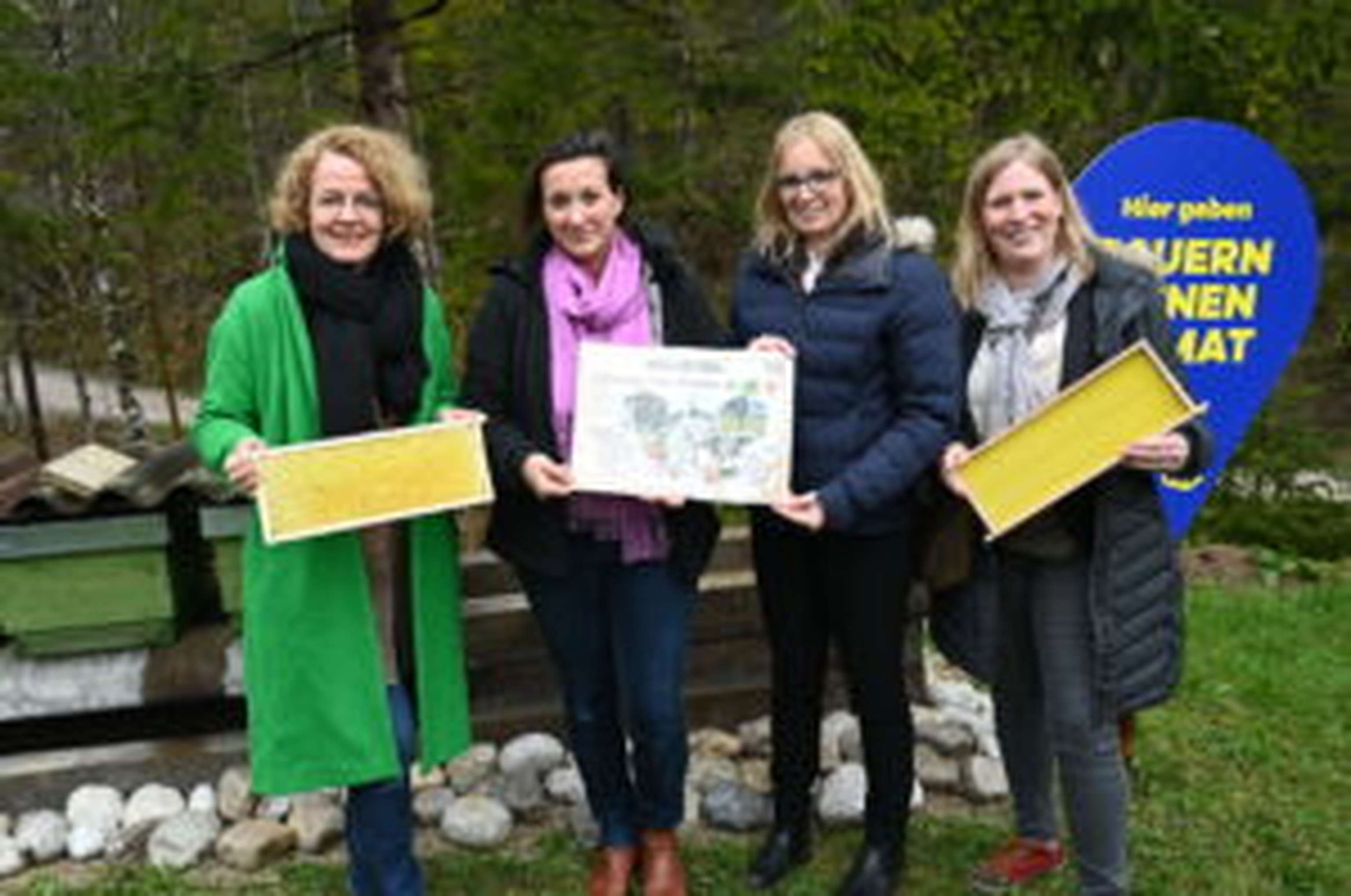 Bildungs-Landesrätin Christiane Teschl-Hofmeister, Fachlehrerin Christina Forsthuber, Bürgermeisterin Manuela Zebenholzer (Gemeinde Hollenstein an der Ybbs) und Bienenbeauftragte Karoline Ofenböck (Verein LandImpulse) bei den Bienenstöcken des Lehrpfades.