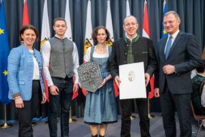 Agrarlandesrätin Michaela Langer-Weninger (l.) und Landeshauptmann Thomas Stelzer (r.) überreichten die Erbhoftafel an Renate und Leopold Ritt-Rammer, die mit Sohn Simon gekommen waren.