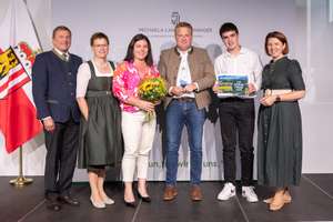 Gewinner der Kategorie Einkommen stehen mit dem Preis und politischen Vertretern auf der Bühne.