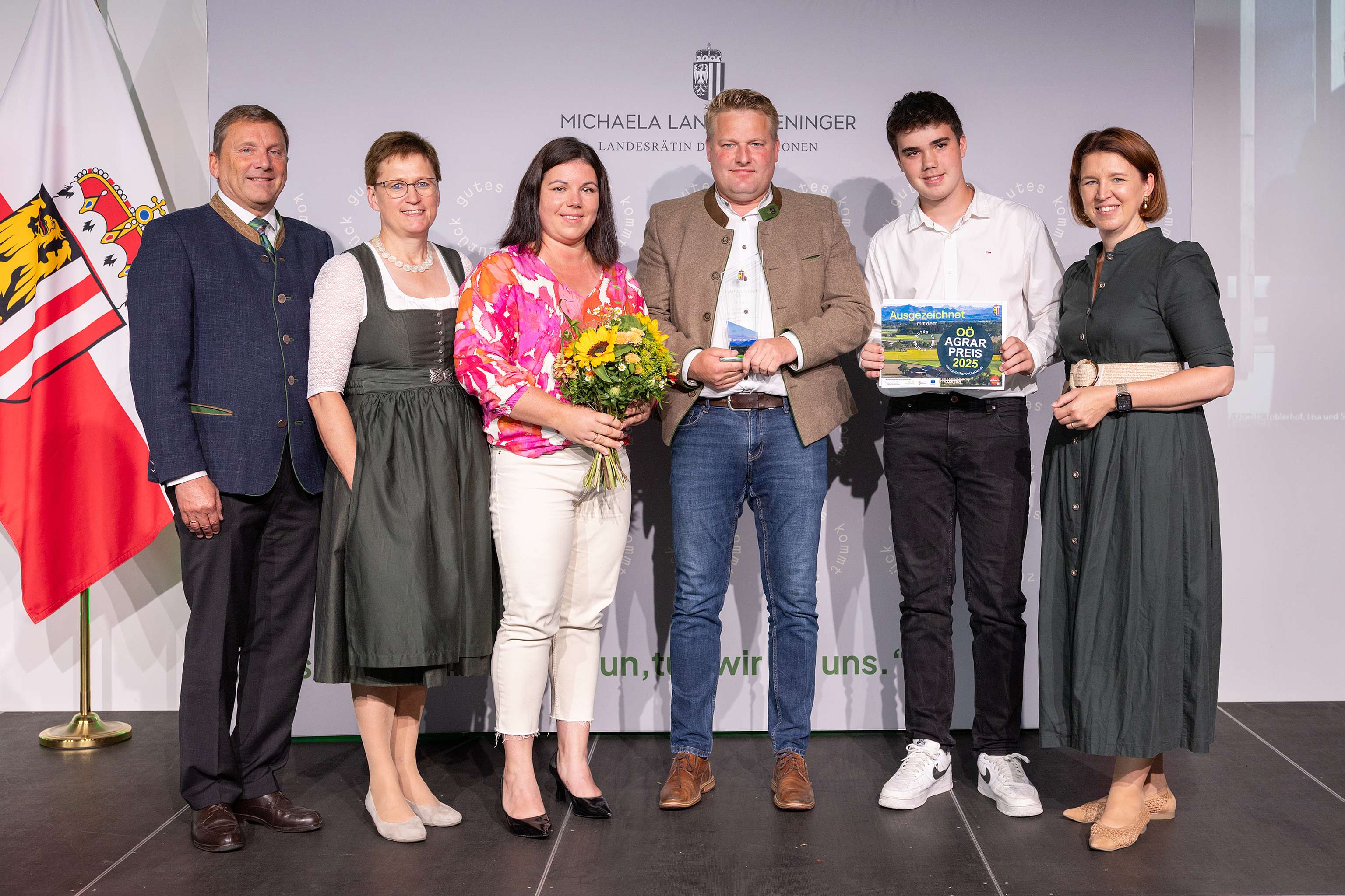 Gewinner der Kategorie Einkommen stehen mit dem Preis und politischen Vertretern auf der Bühne.