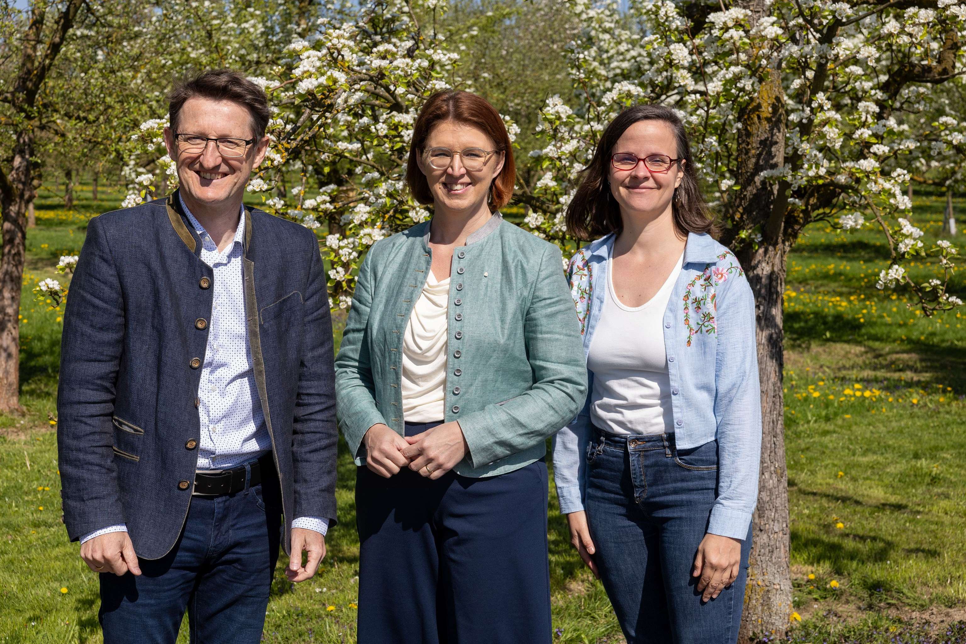 Rainer Silber, Michaela Langer Weninger und Theresa Frühwirth vor blühenden Obstbäumen.