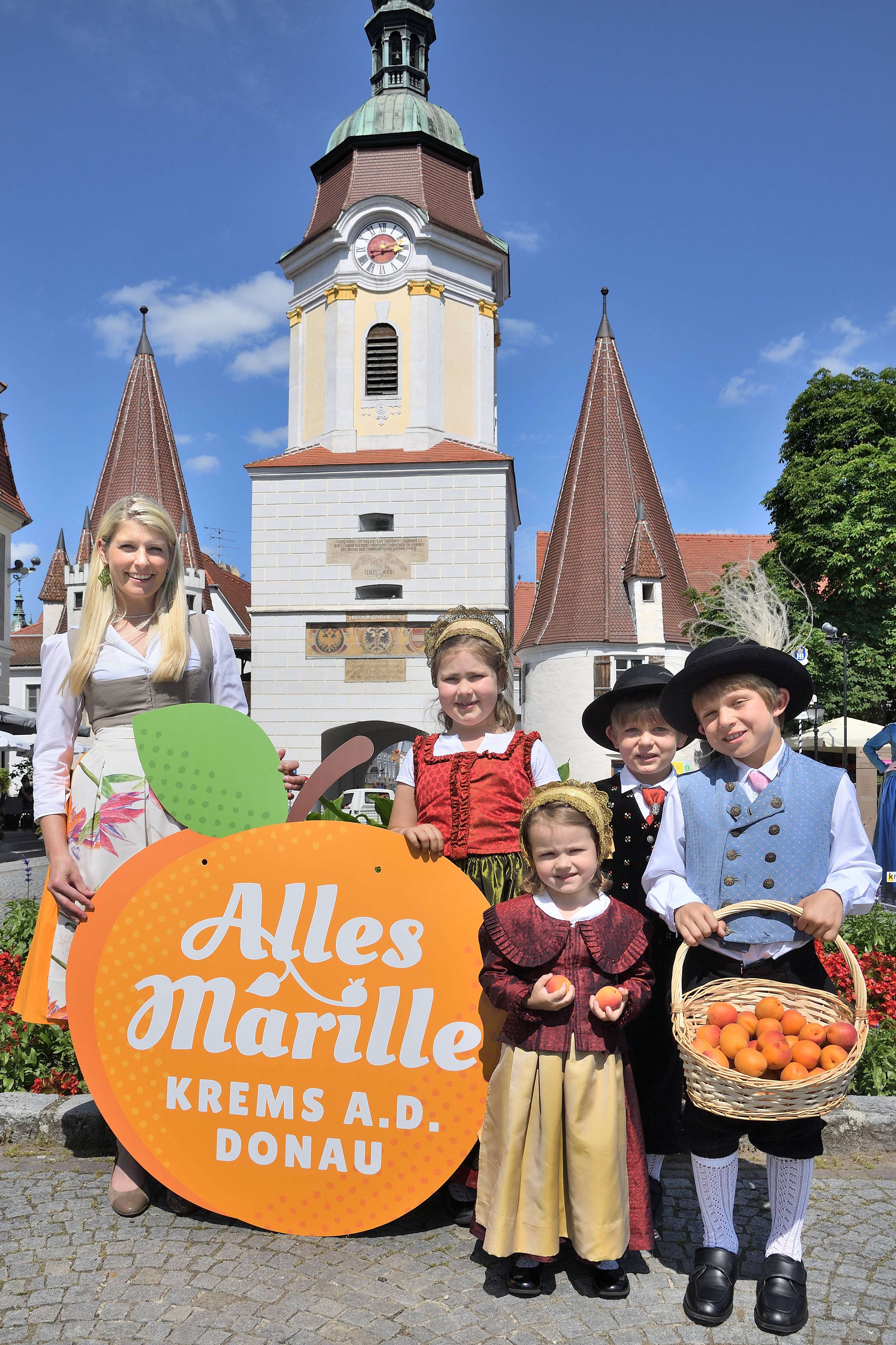 Kinder in Tracht mit Marillen in der Hand