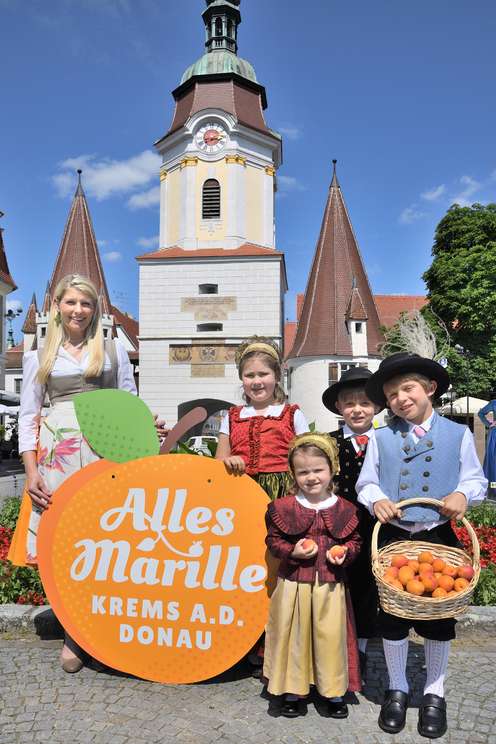 Kinder in Tracht mit Marillen in der Hand