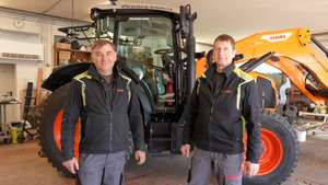 Zwei Männer vor einem Claas-Traktor stehend.