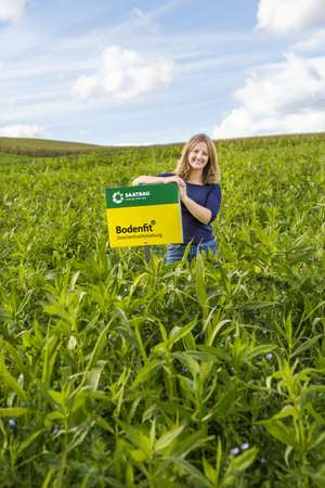 Dame mit einem Saatbau-Schild in einem Feld