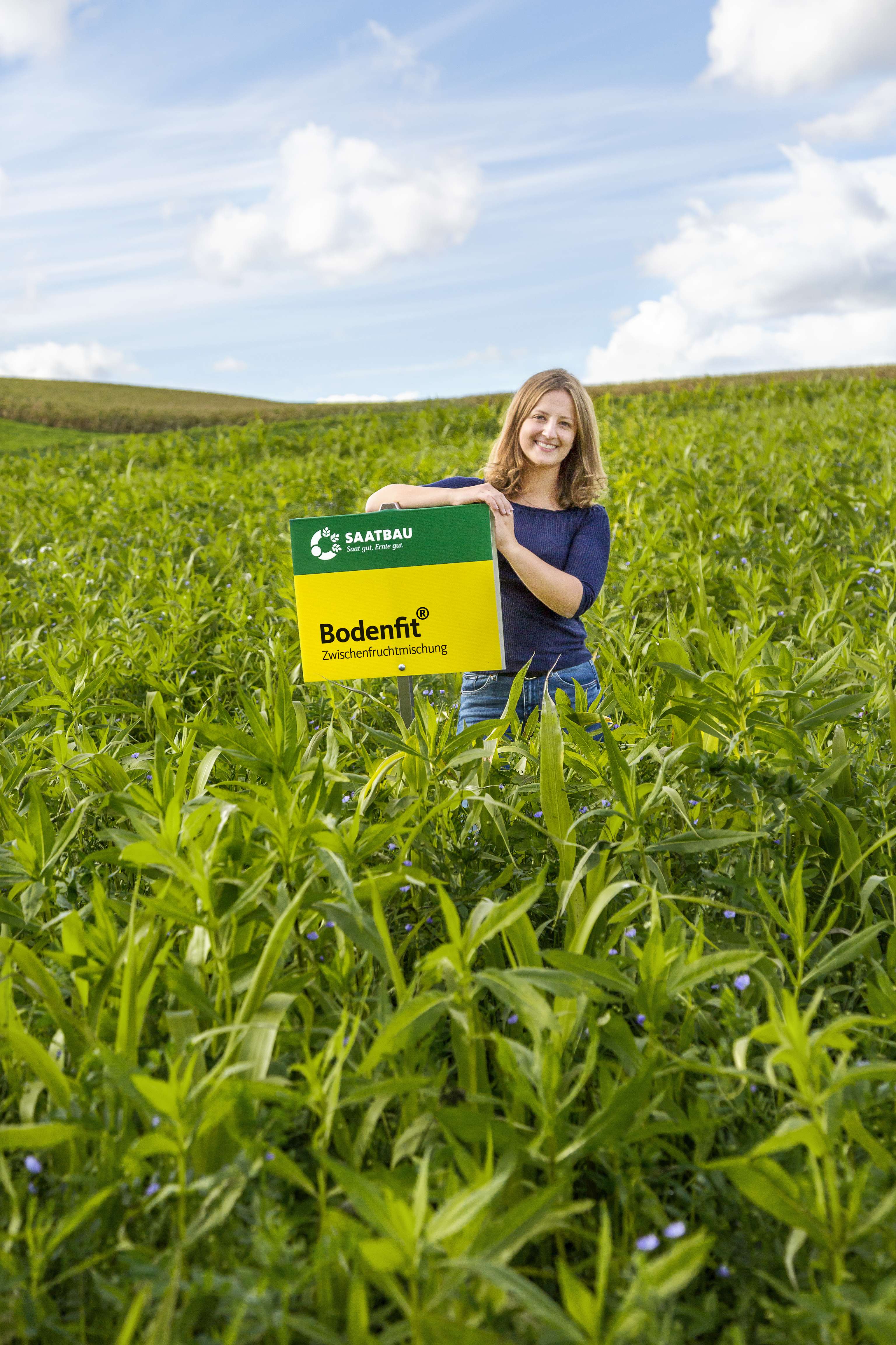 Dame mit einem Saatbau-Schild in einem Feld