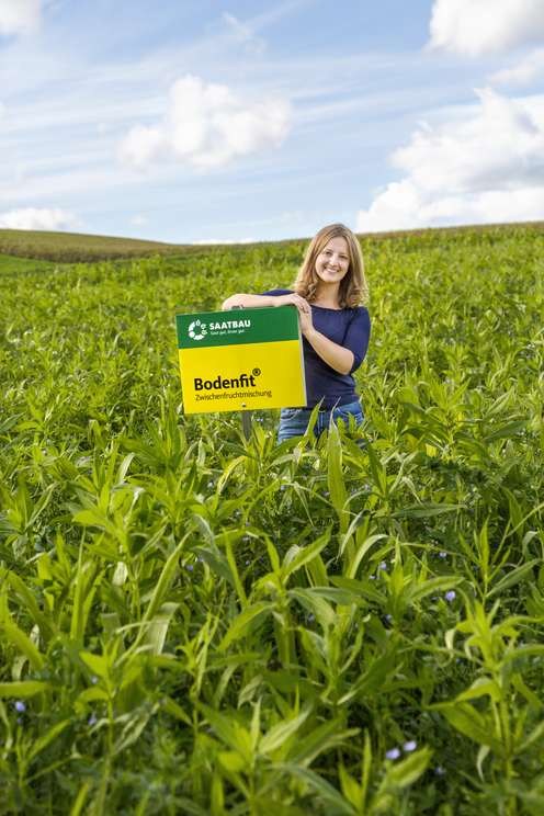 Dame mit einem Saatbau-Schild in einem Feld