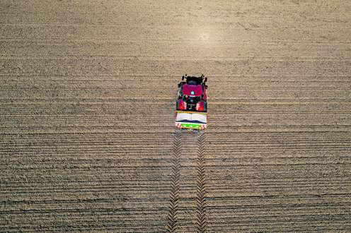 Traktor fährt auf Feld um zu düngen.