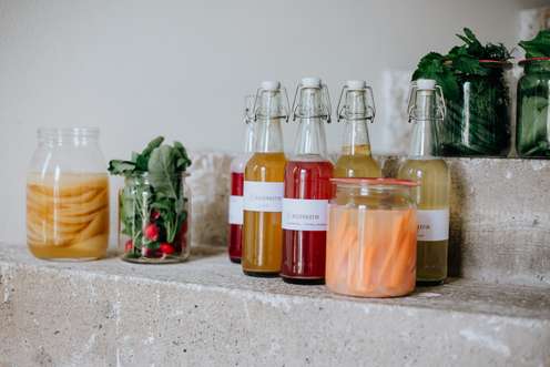 Gläser und Flaschen mit fermentiertem Gemüse und Säften