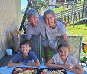 Familie feiert 10. Geburtstag im Freien mit Torte, Snackplatten mit Obst und Wurst sowie zwei lächelnden Kindern und Großeltern.