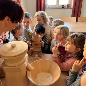 Kinder beim Quetschen von Getreide zu Flocken.