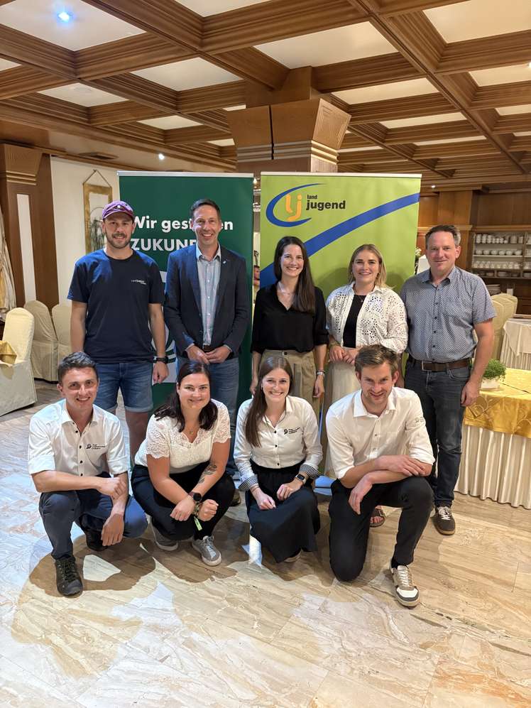 Gruppenfoto von neun Personen vor Landjugend-Rollups in einem Festsaal, zwei Reihen, lächelnd in die Kamera.