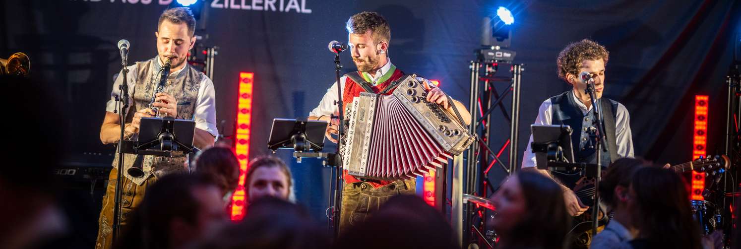 Die Band Sagg'risch aus dem Zillertal spielt live auf der Bühne mit Klarinette und Akkordeon in Tracht.