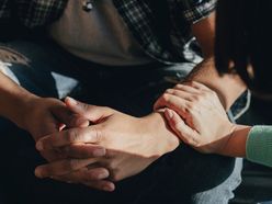 Mann sitzt mit verschränkten Armen und wird von einer Frau getröstet