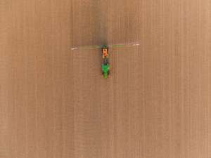 Traktor fährt mit Feldspritze über ein noch unbestelltes Feld