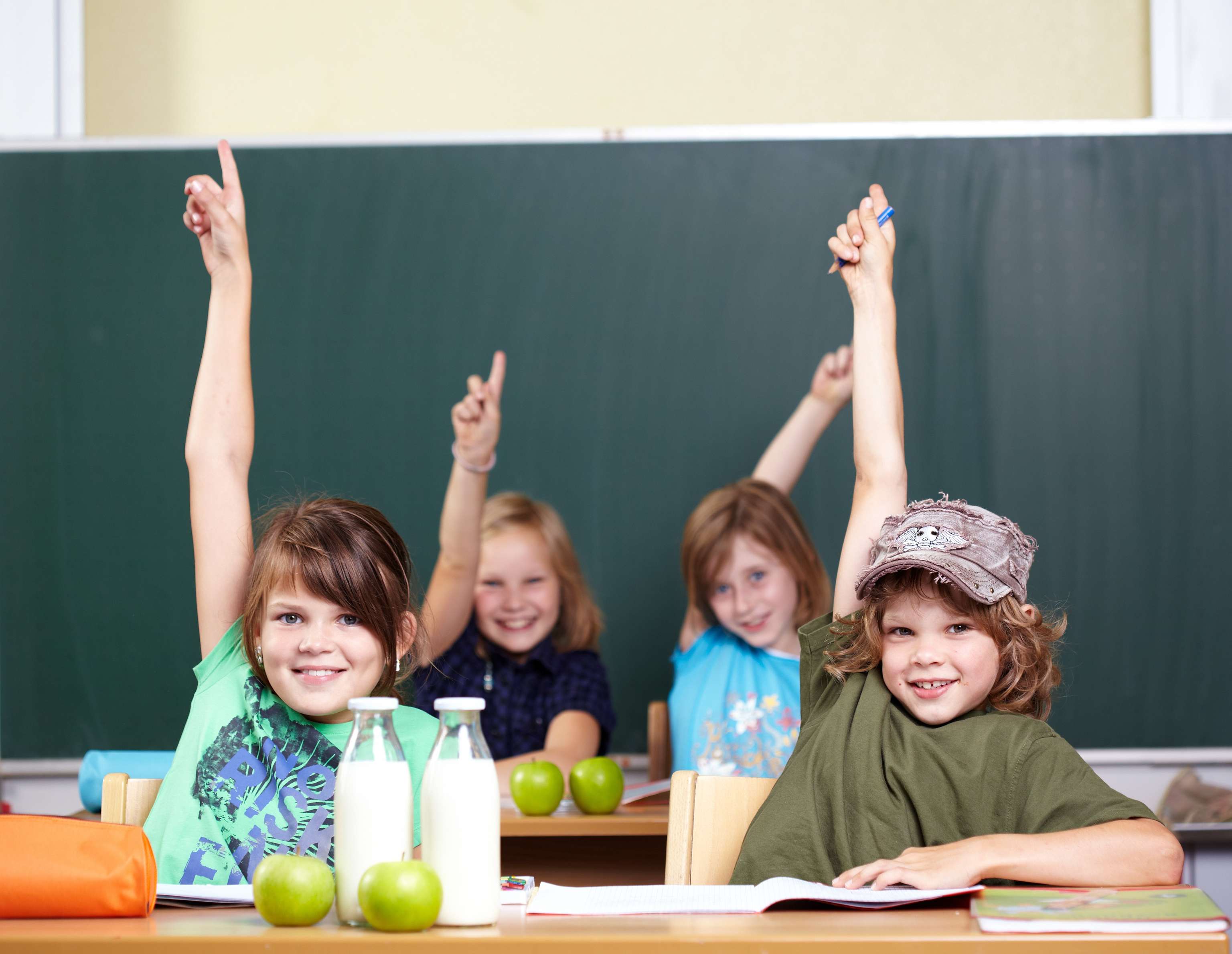 Schulkinder in der Klasse melden sich per Handzeichen.