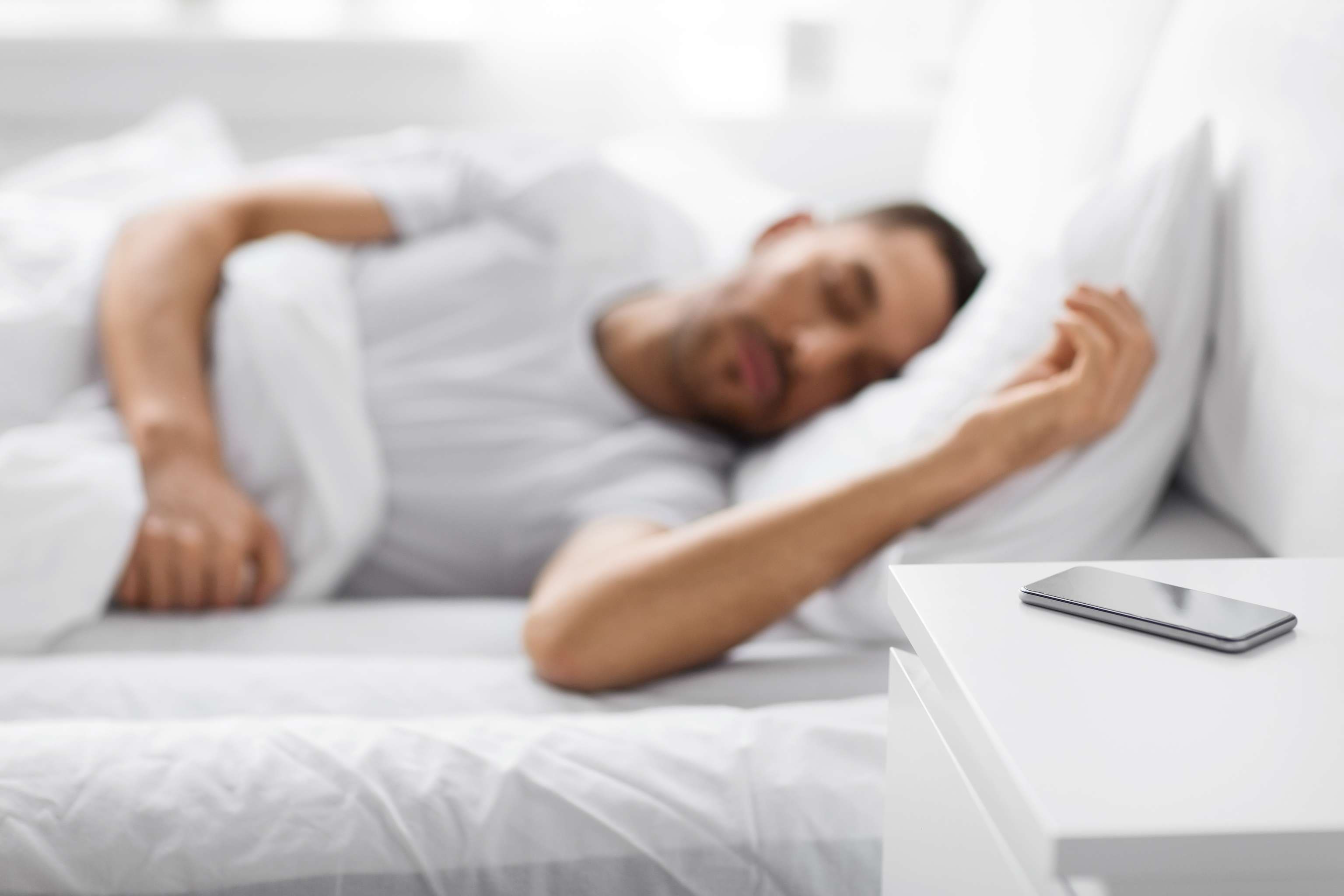 Mann schläft Handy liegt am Nachttisch