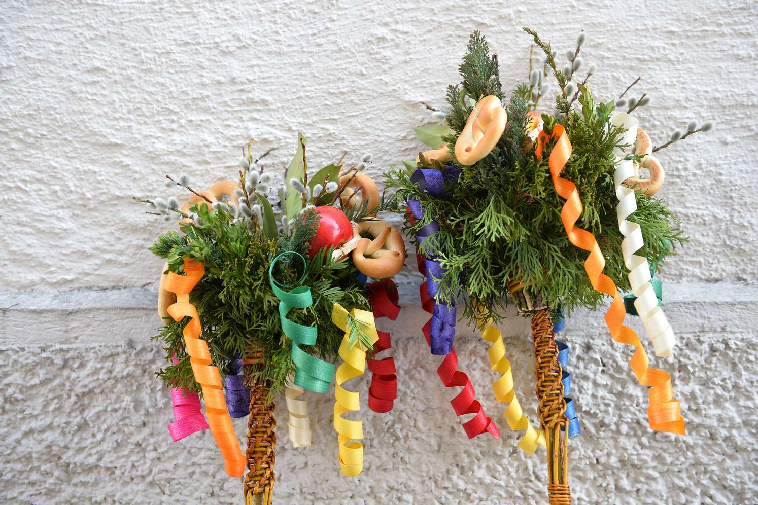 Zwei Palmbuschen, geschückt mit bunten Bändern und Brezeln.
