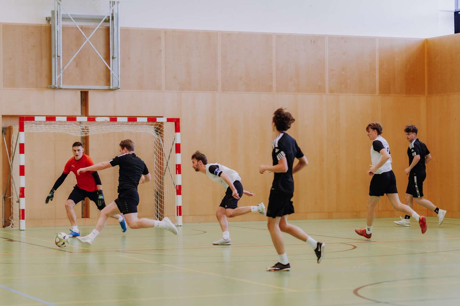 Junge Männer spielen Fußball in der Turnhalle.