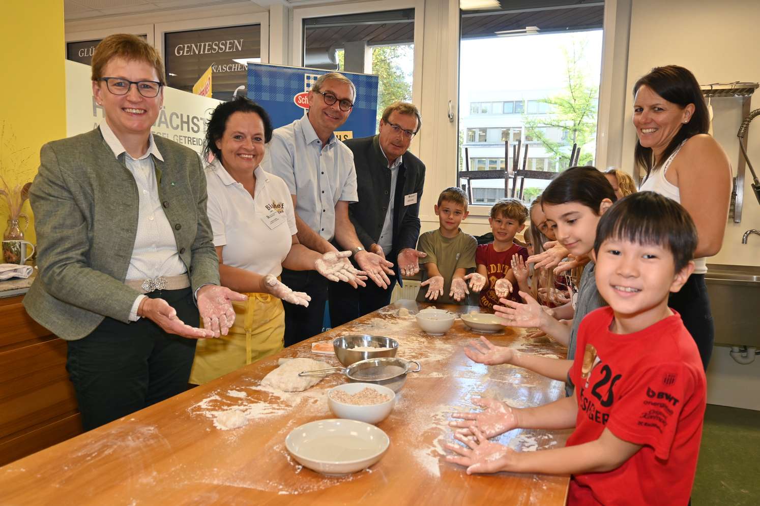 Rosemarie Ferstl, Johanna Haider, Franz Waldenberger und Hannes Gruber mit Kindern und der Lehrerin einer Volksschulklasse beim Teigkneten.