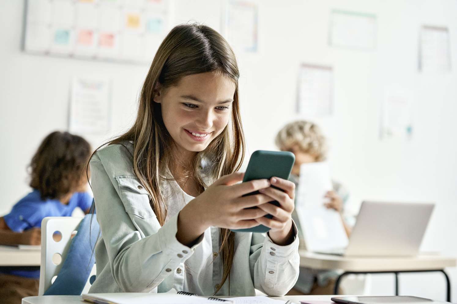 Kind mit Handy im Klassenzimmer