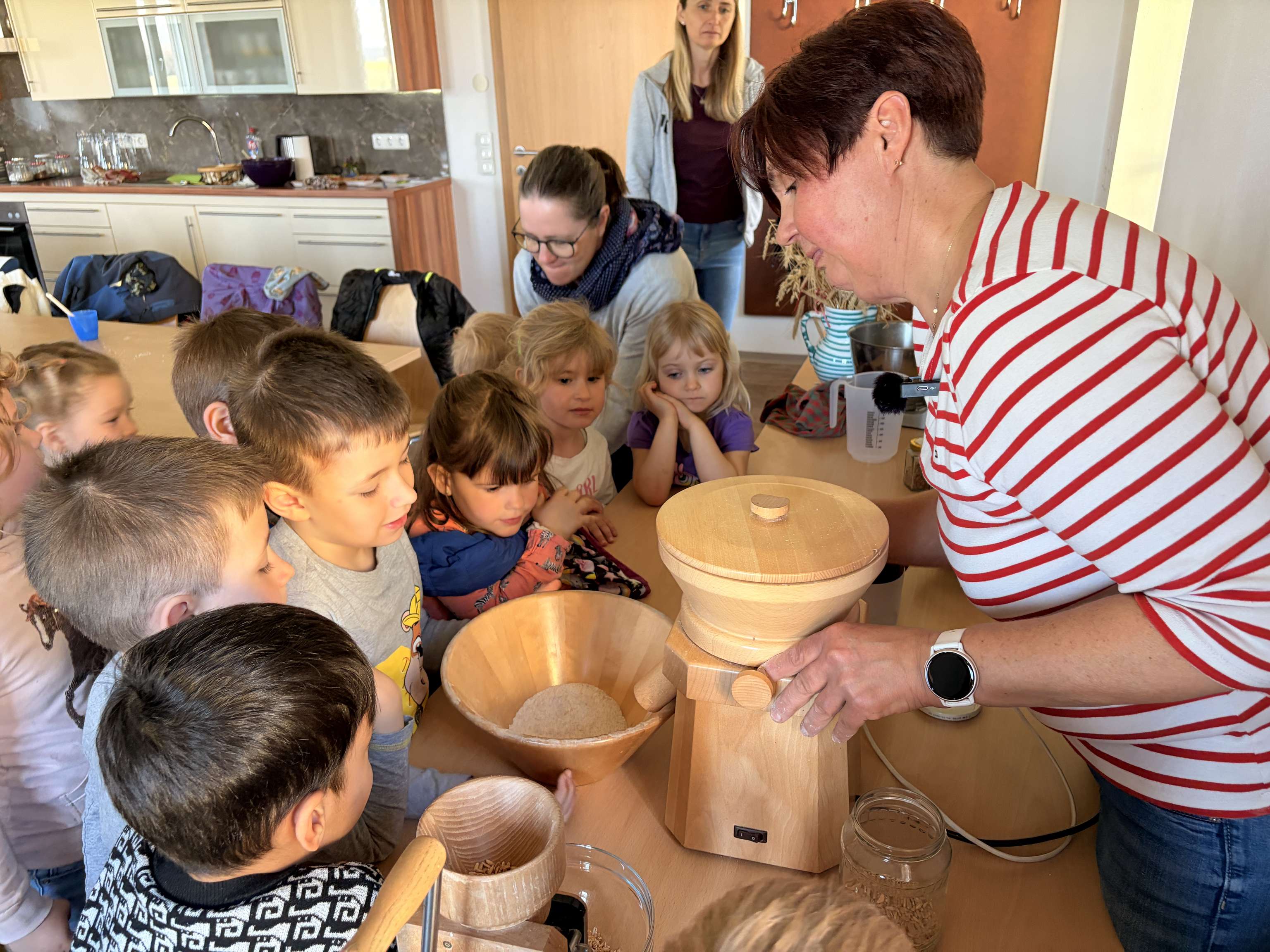Kinder schauen beim Mahlen von Getreide zu.