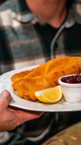 Ein Wiener Schnitzel mit Preiselbeeren und Kartoffelsalat wird serviert
