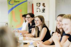 Jugendliche sitzen am Tisch und lachen
