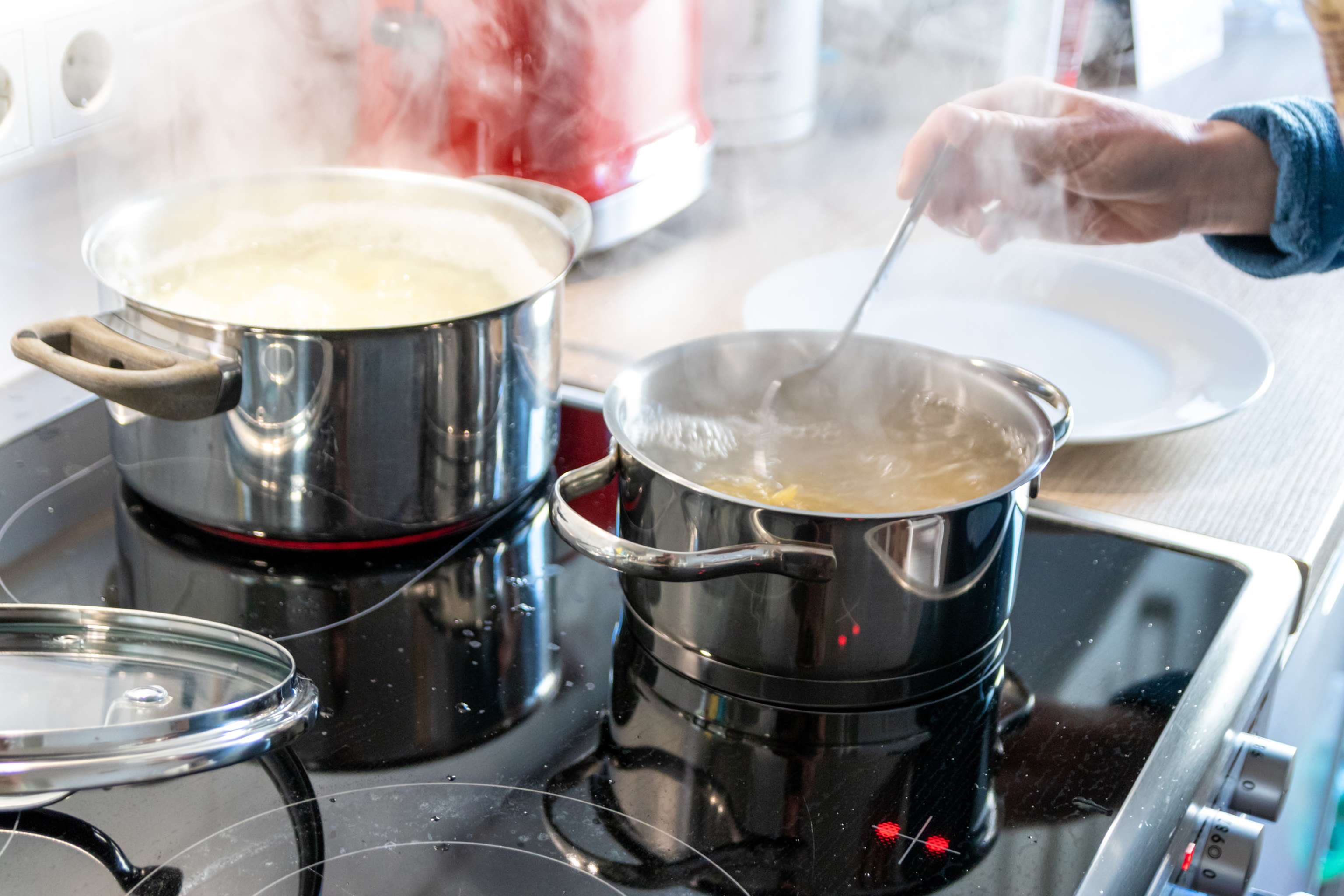 Hausfrau Kocht Nudeln Und Wasser Für Das Mittagessen Mit Der Familie In Silbernen Töpfen Auf Induktionsherd Mit Heißen Kochfeldern Als Leckeres Mahl