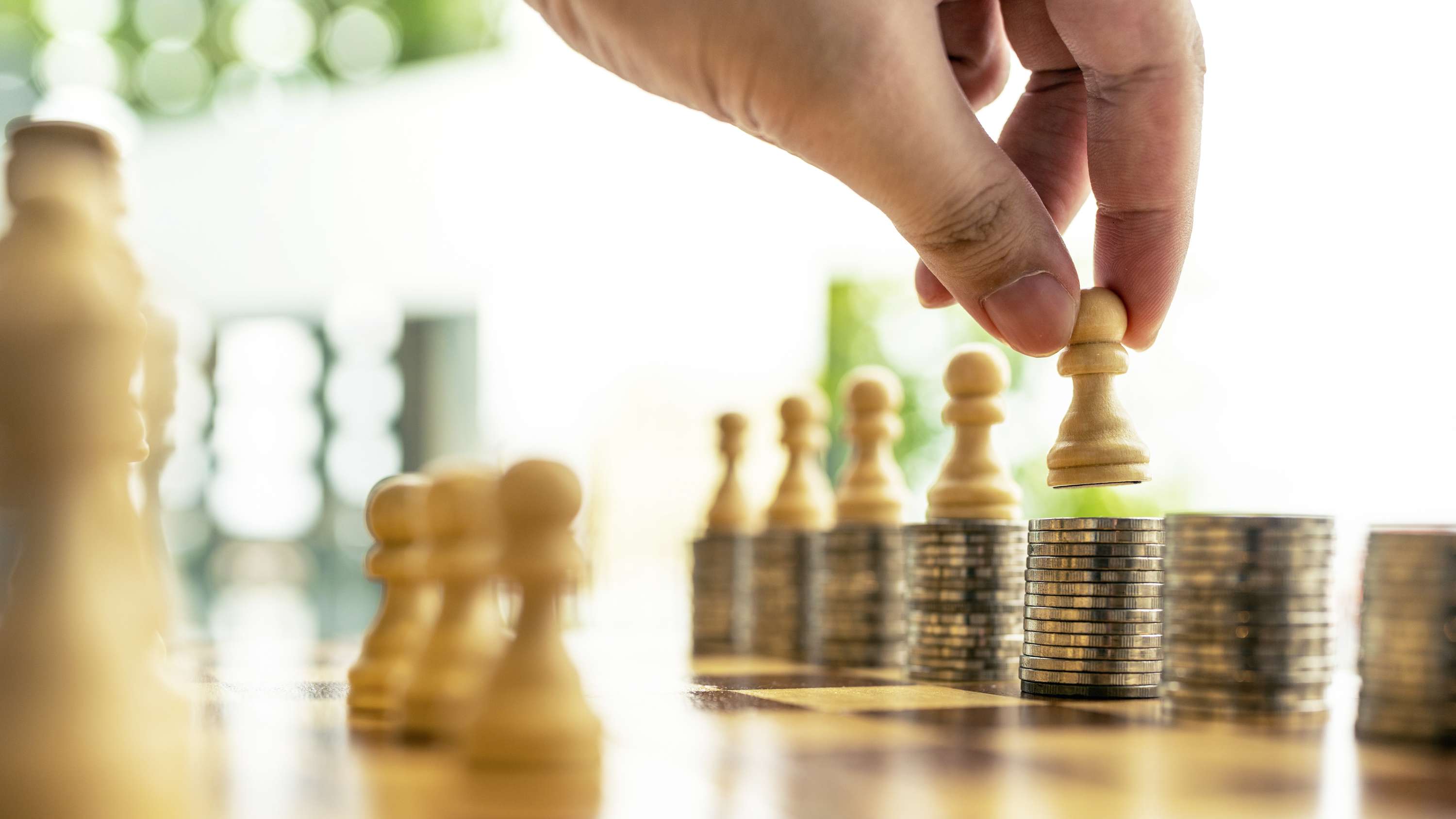 Eine Person stellt den Bauern beim Schach auf Münzen