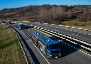 4 blaue LKW mit Milch fahren hintereinander auf der Autobahn in einer herbstlichen Landschaft