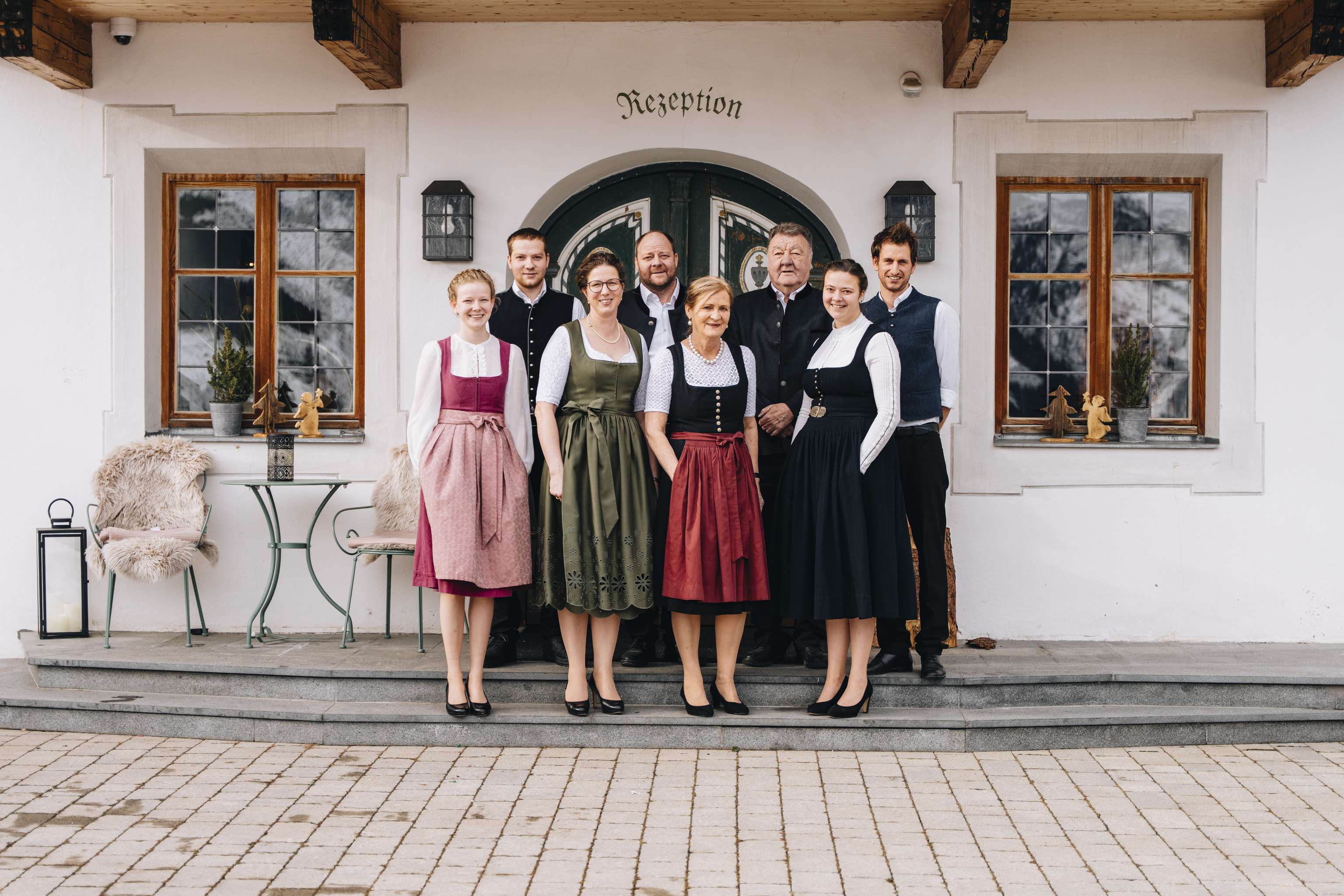 Eine Gruppe von Menschen in traditioneller Kleidung steht vor einem Gebäude mit der Aufschrift "Rezeption".