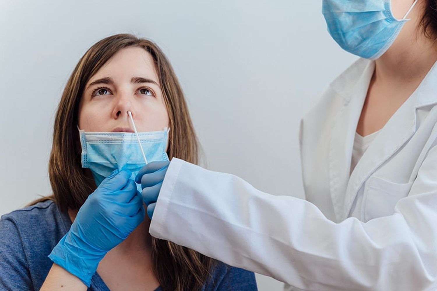 Female Doctor In A Protective Suit Taking A Nasal Swab From A Pe