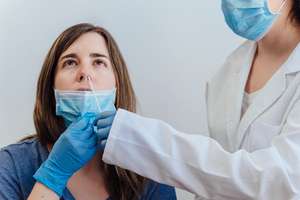 Female Doctor In A Protective Suit Taking A Nasal Swab From A Pe