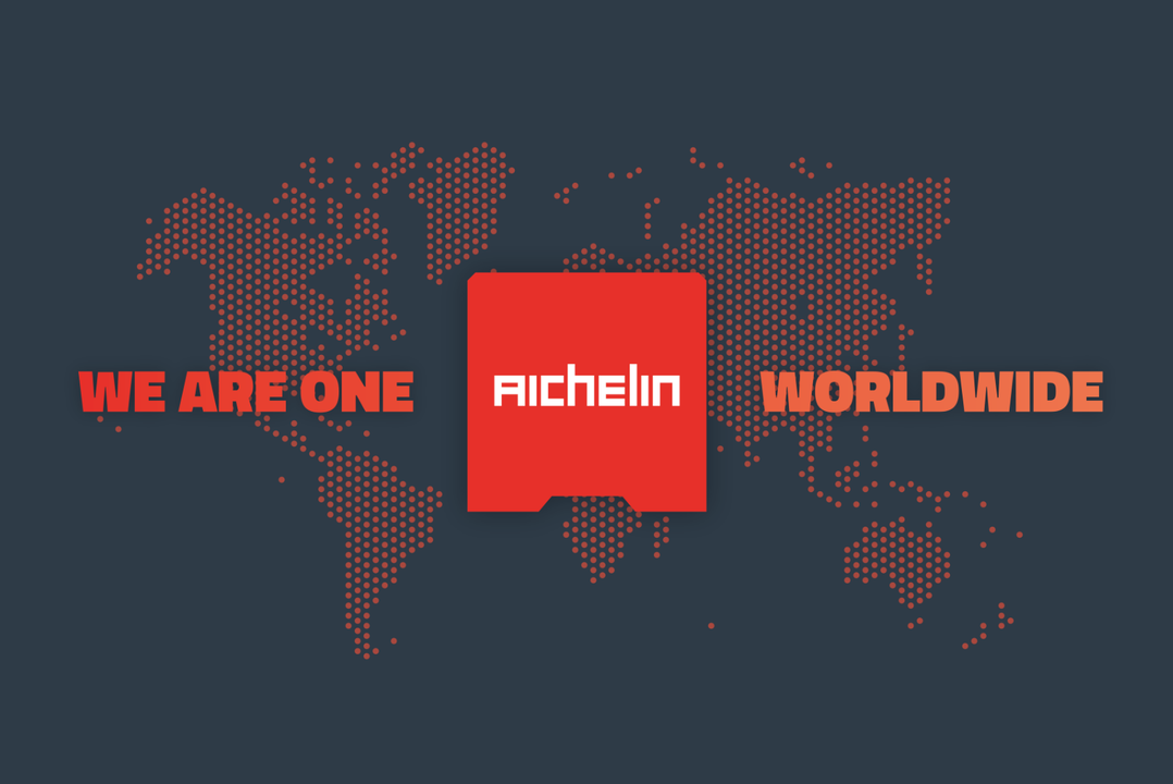 Stylized world map with the text "We Are One Worldwide" and a red square featuring "Aichelin" in the center.