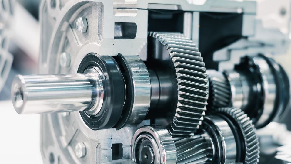 Close-up of a mechanical gearbox showing interlocking metal gears and shafts, highlighting engineering precision and machinery components.