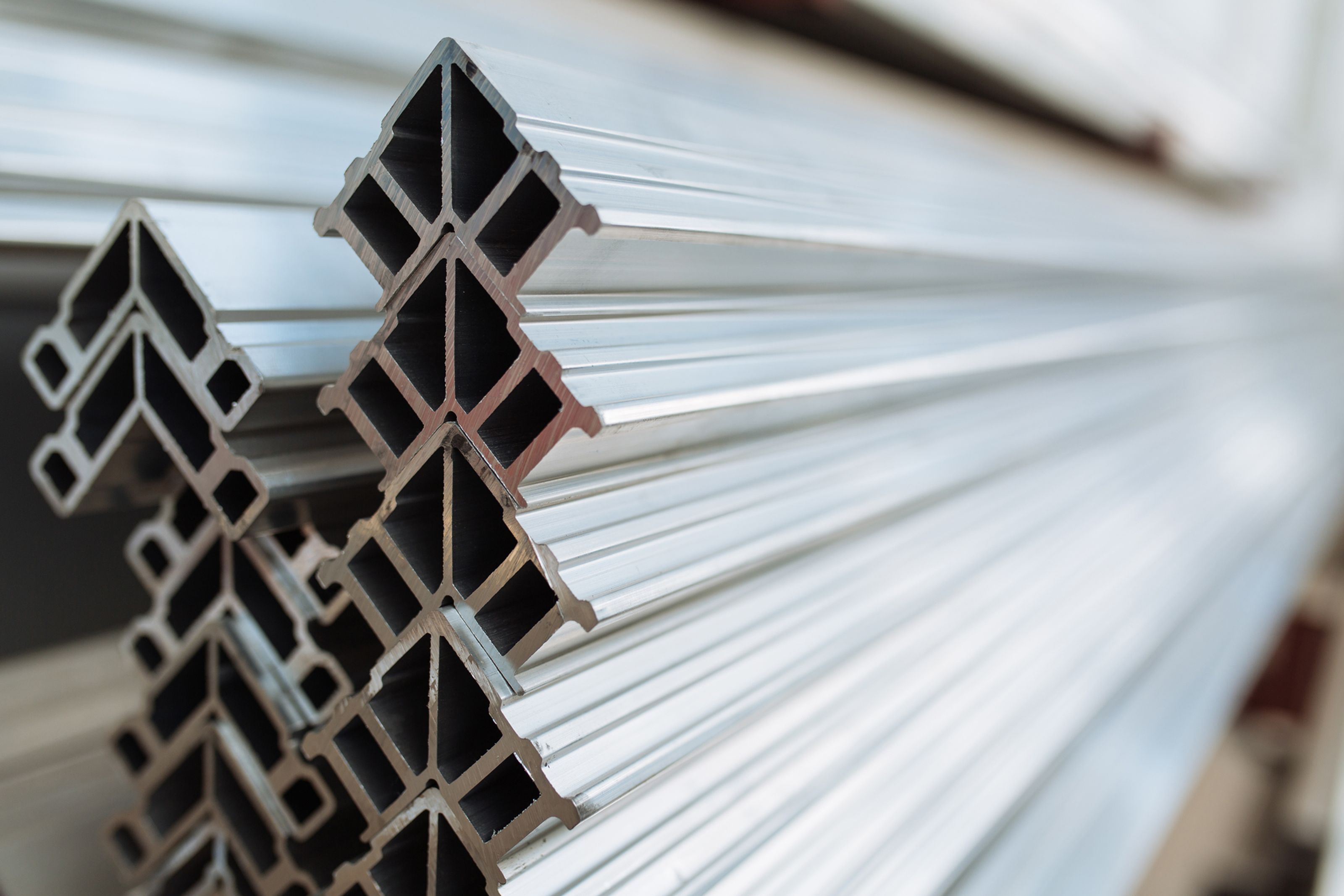 Close-up of stacked aluminum profiles with a geometric, cross-sectional design. The shiny, reflective surfaces emphasize their metallic texture.