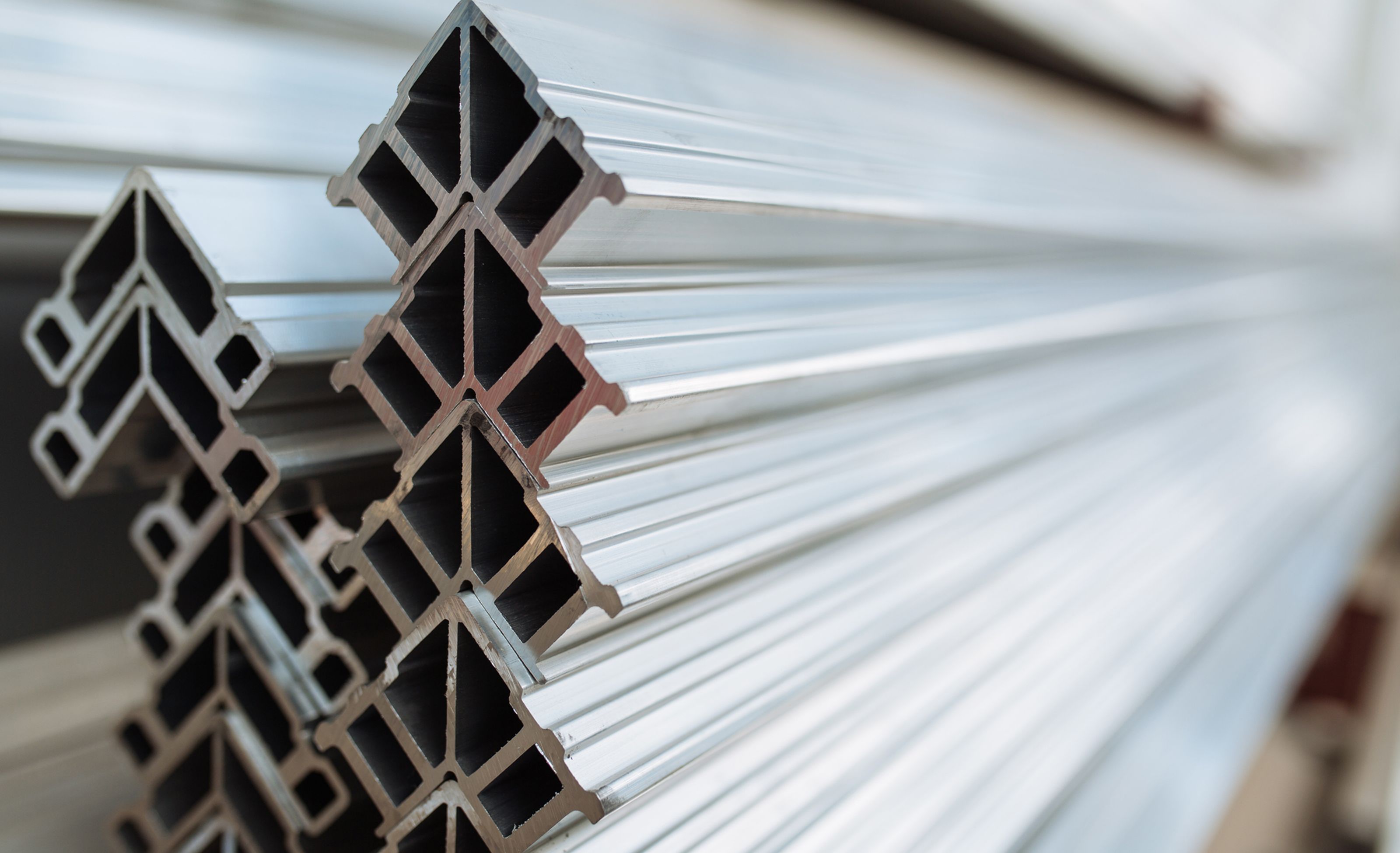Close-up of stacked aluminum profiles with a geometric, cross-sectional design. The shiny, reflective surfaces emphasize their metallic texture.