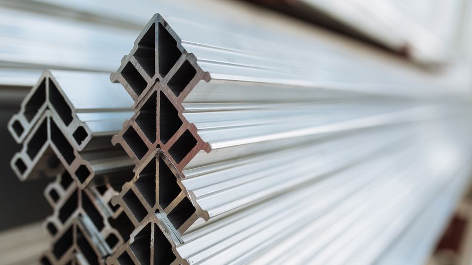 Close-up of stacked aluminum profiles with a geometric, cross-sectional design. The shiny, reflective surfaces emphasize their metallic texture.