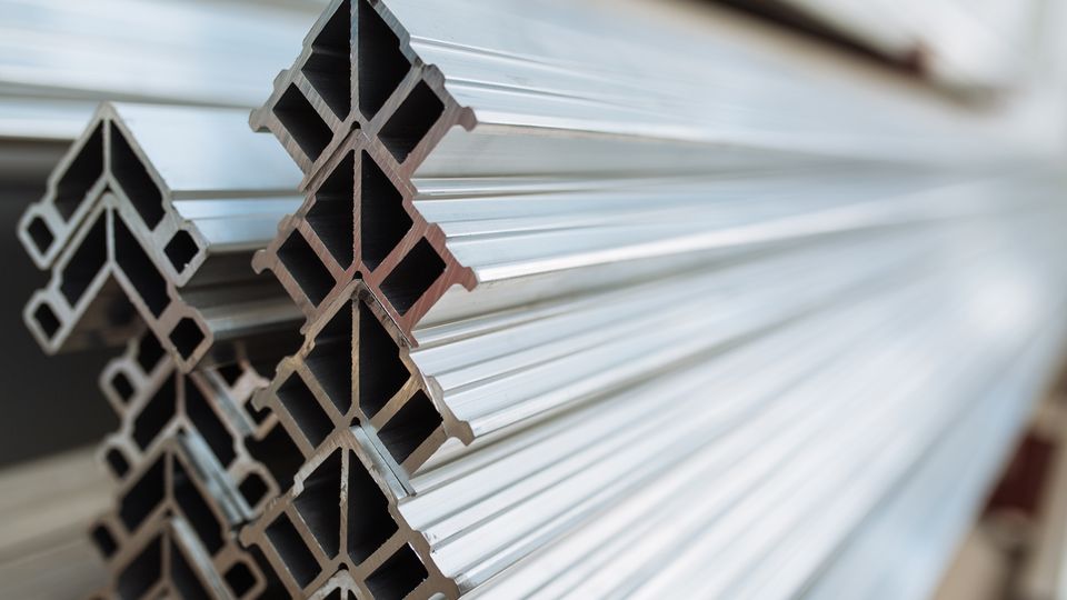 Close-up of stacked aluminum profiles with a geometric, cross-sectional design. The shiny, reflective surfaces emphasize their metallic texture.