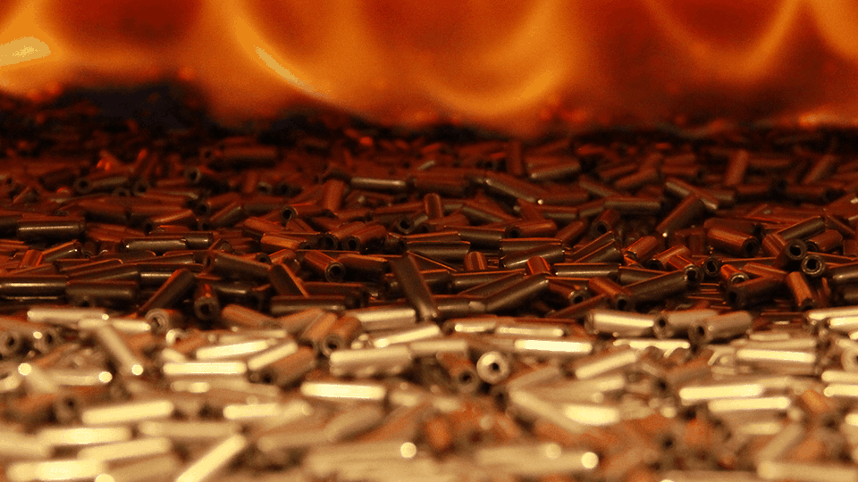 Close-up of cylindrical bullets scattered with a blurred fiery orange background.