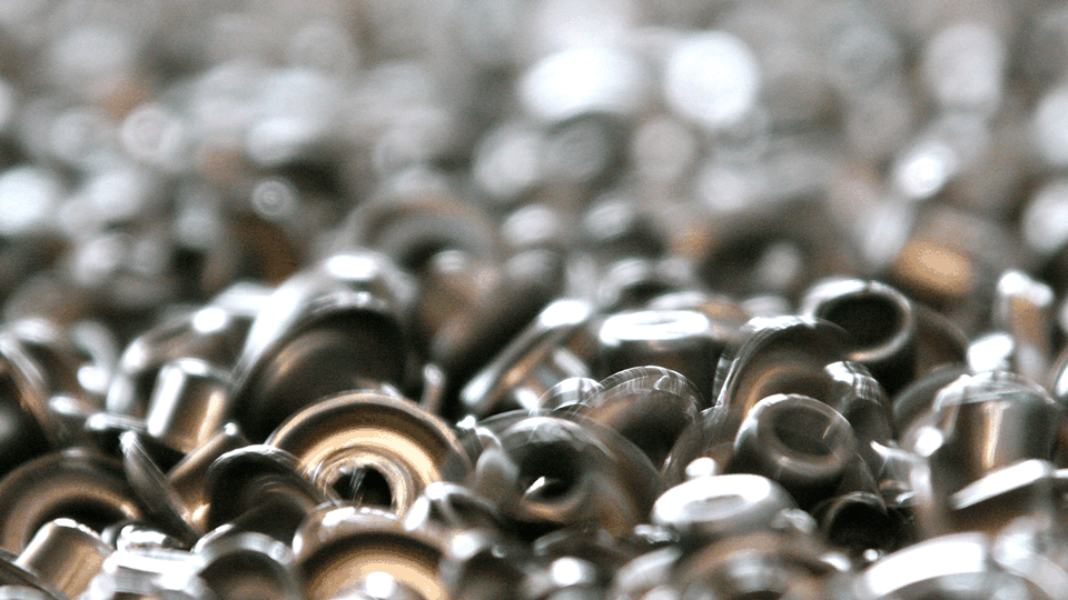 Close-up view of a pile of shiny metal shavings with a blurred background, creating an abstract and industrial texture.