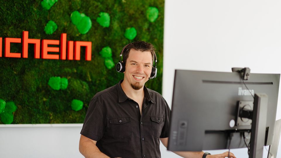 Mann steht mit Heatset am Computer